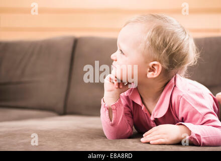 Baby girl sdraiato sul divano pensando profilo laterale Foto Stock