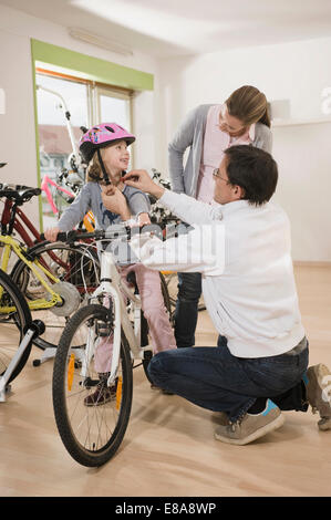 Venditore aiutare ragazza di indossare il casco in bicicletta Foto Stock