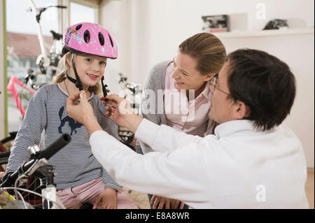 Venditore aiutare ragazza di indossare il casco in bicicletta Foto Stock