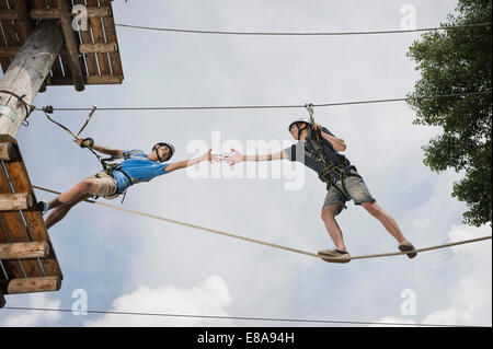 Adolescente in una rupe di arrampicata aiutando un altro Foto Stock