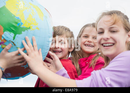 Fratelli e sorelle holding globe sorridendo a palloncino Foto Stock