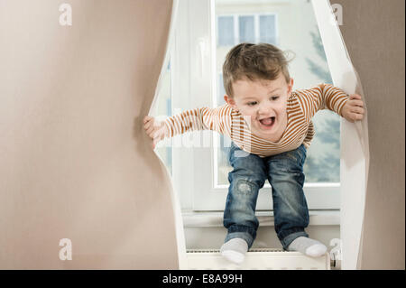 Ragazzo giocando con tendina Foto Stock