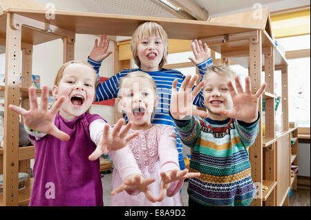 Quattro figli con le braccia tese urlando Foto Stock