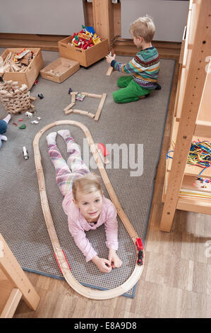 Bambina giocando con la ferrovia in legno nel suo kindergarten Foto Stock