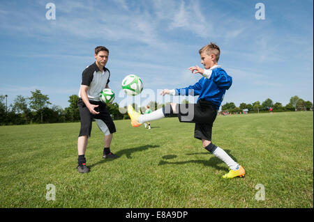 Soccer trainer insegnare ai giovani player aiutando Foto Stock