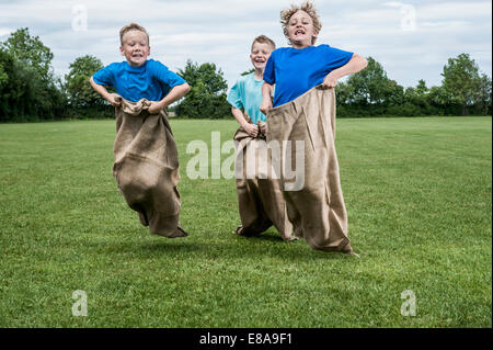 Tre giovani ragazzi in esecuzione in sackrace jumping Foto Stock