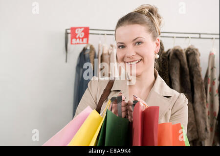 Ritratto di giovane donna azienda shopping bags, sorridente Foto Stock