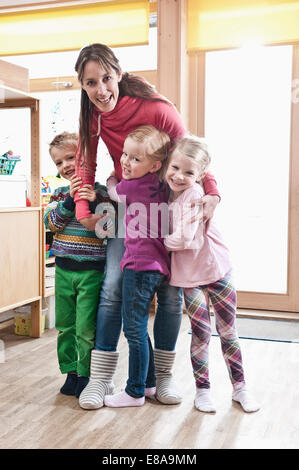 Foto di un gruppo di insegnanti di sesso femminile e tre bambini in piedi in kindergarten Foto Stock