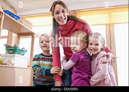 Foto di un gruppo di insegnanti di sesso femminile e 3 bambini in una scuola materna Foto Stock