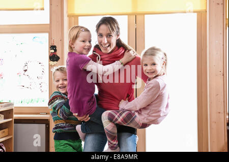 Educatore femmina scatenandosi con tre bambini in una scuola materna Foto Stock