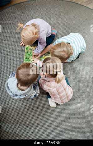 Quattro bambini guardando sul terreno della sua scuola materna, vista in elevazione Foto Stock