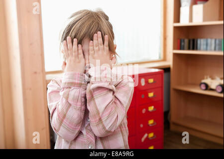 Bambina che copre il volto con le mani Foto Stock