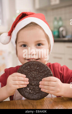 Ragazza mangiare gingerbread cookie, sorridente, ritratto Foto Stock