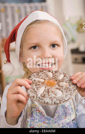 Ragazza mangiare gingerbread cookie, sorridente, ritratto Foto Stock