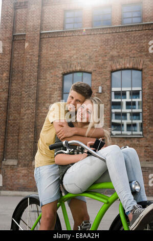 Ritratto di giovane adolescente abbracciando in bicicletta, sorridente Foto Stock