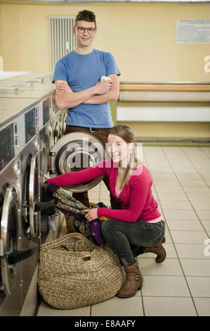 Coppia giovane riempiendo i panni in lavatrice Foto Stock