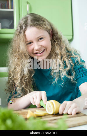 Ragazza in cucina per affettare il limone Foto Stock