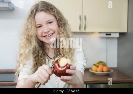 Ragazza in cucina peeling apple Foto Stock