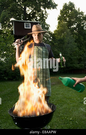 Pericolo di incendio versando spirito metilato su barbecue Foto Stock