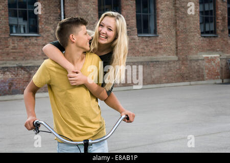 Giovane adolescente abbracciando in bicicletta, sorridente Foto Stock