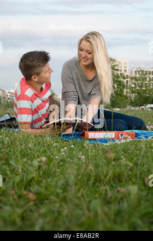 Giovane adolescente studiare nel parco, sorridente Foto Stock