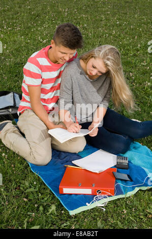 Giovane adolescente facendo i compiti in posizione di parcheggio Foto Stock