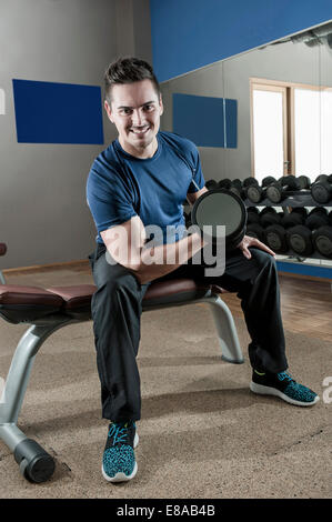 Giovane uomo in palestra il sollevamento di pesi Foto Stock