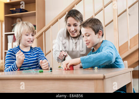 Ritratto di due ragazzi giocare e babysitting femmina assistant Foto Stock