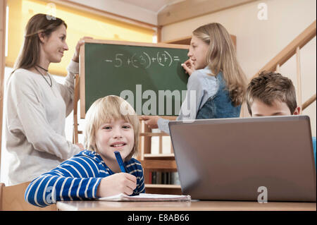 Femmina assistente di puericultura aiutando i bambini da studiare Foto Stock