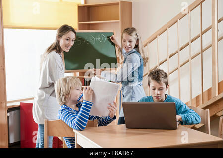 Femmina assistente di puericultura aiutando i bambini da studiare Foto Stock