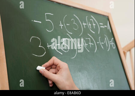 Ragazza di scrittura problema aritmetico sulla lavagna Foto Stock