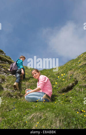 Giovane ragazza seduta su erba fratello Alpi arrampicata Foto Stock