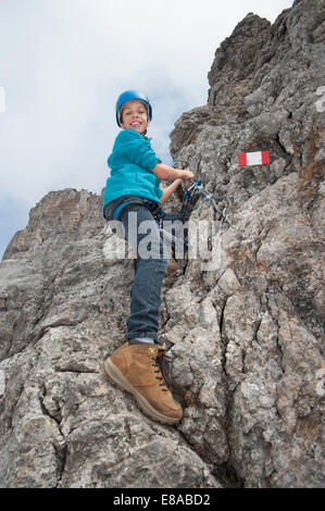 Giovane ragazzo adolescente tenendo la corda sulla parete di roccia Foto Stock