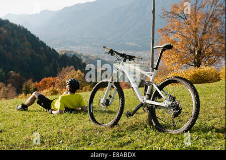 Mountainbiker in appoggio sull'erba godendo di view Foto Stock