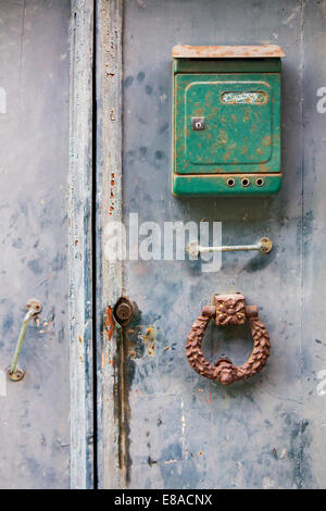 Il verde di una cassetta postale e porta in ferro respingente sul vecchio porte in legno Foto Stock