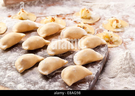 Vareniki canederli con patate e cipolla. Non cotti sulla scrivania in legno. Foto Stock