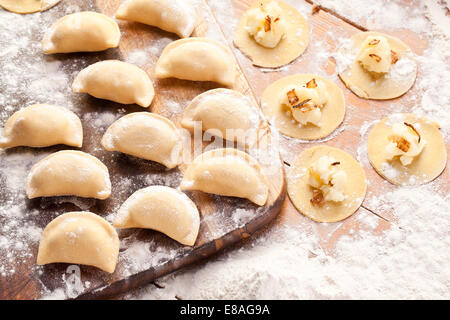 Vareniki canederli con patate e cipolla. Non cotti sulla scrivania in legno. Foto Stock