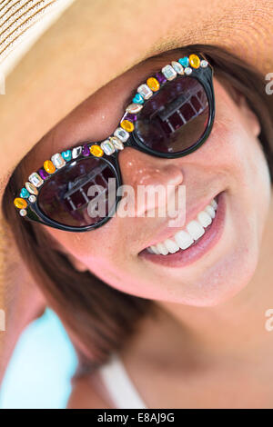 Close up ritratto di giovane donna che indossa gli occhiali da sole e cappello Foto Stock