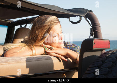 Giovane donna appoggiata sulla finestra jeep a costa, Malibu, California, Stati Uniti d'America Foto Stock
