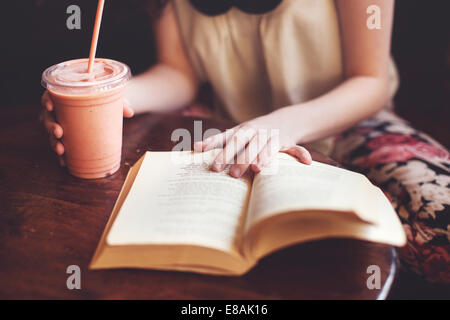 Donna che legge un libro sul tavolo Foto Stock