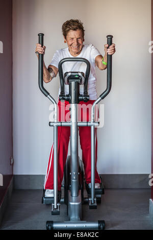 Ritratto di una donna senior utilizzando una macchina ginnica Foto Stock