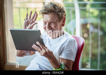 Un molto alti donna utilizzando tavoletta digitale su Appartamento balcone Foto Stock