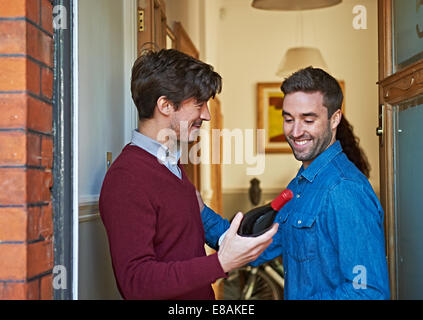 Gli uomini con una bottiglia di vino a sorridere a sportello anteriore Foto Stock