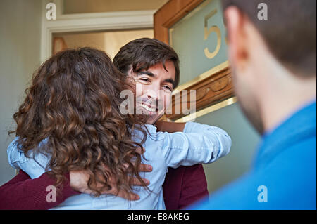 L'uomo accogliente amici davanti alla porta di casa Foto Stock