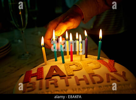 Illuminazione a mano candele sulla torta di compleanno Foto Stock