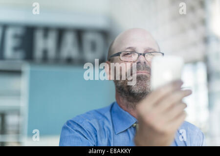 Imprenditore maturo che indossano occhiali tramite telefono cellulare Foto Stock