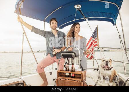 Metà adulto giovane sulla barca a vela con il cane Foto Stock