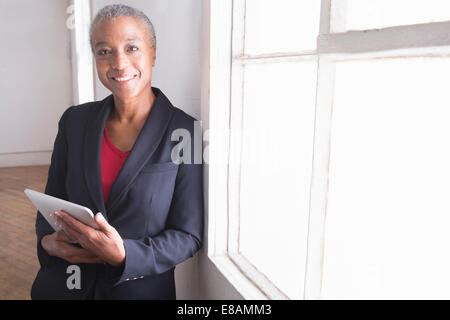 Donna matura azienda digitale compressa, ritratto Foto Stock