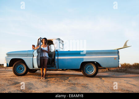 Ritratto di giovane donna surfer appoggiata su pick up truck porta, Leucadia, CALIFORNIA, STATI UNITI D'AMERICA Foto Stock