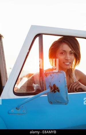 Ritratto di giovane donna surfer attraverso pick up truck finestra, Leucadia, CALIFORNIA, STATI UNITI D'AMERICA Foto Stock